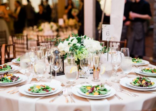 Beautiful Wedding Reception Table Decorated with Salad, Napkins, and Glasses and Flower Arrangement Centerpiece